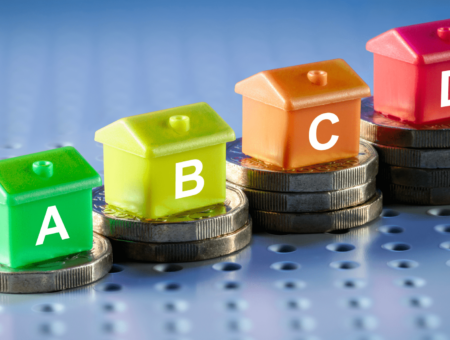 Model houses with the letters 'A', 'B', 'C' & 'D' sat on piles of pound coins.