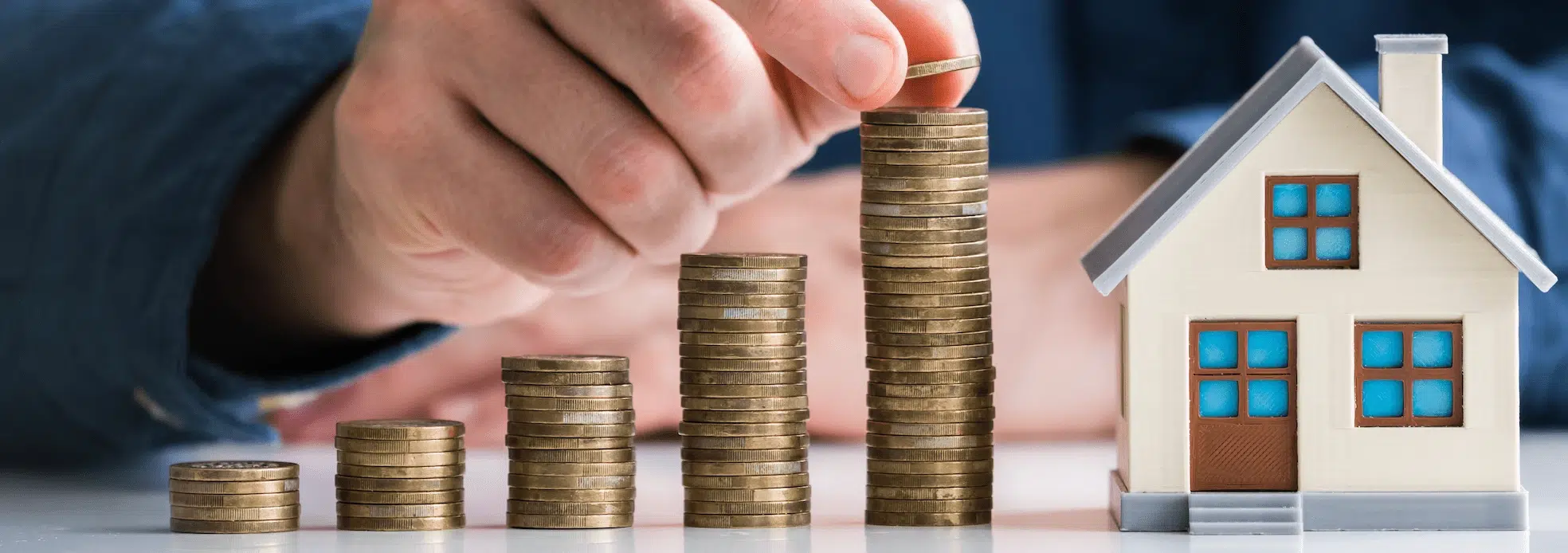 Multiple stacks of coins increasing in height near a model house