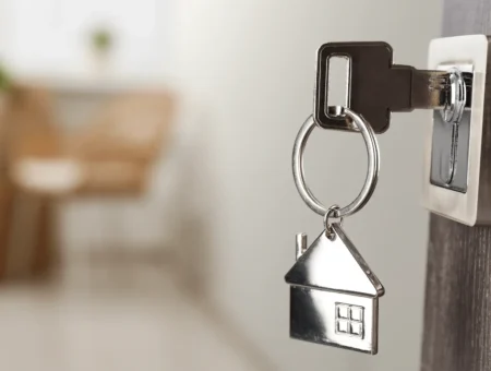 Key hanging in the lock to the door, with a silver house keyring