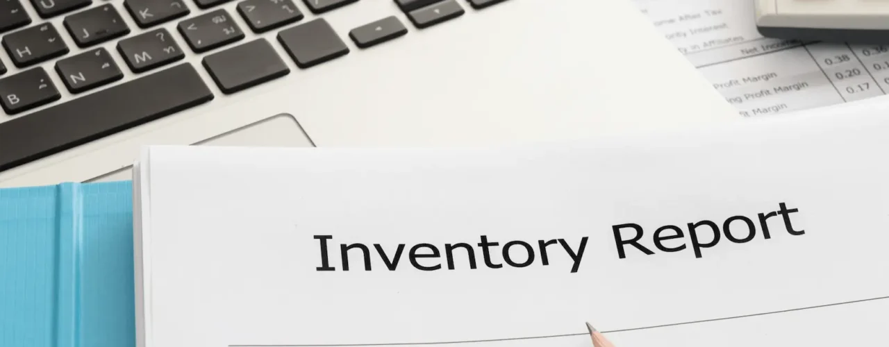 An inventory report document next to a silver laptop