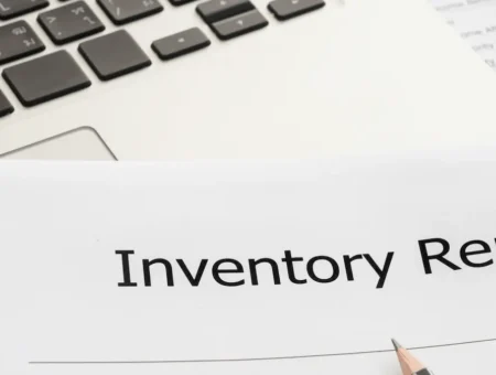 An inventory report document next to a silver laptop