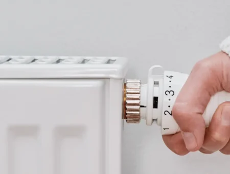 A person changing the setting on a white radiator