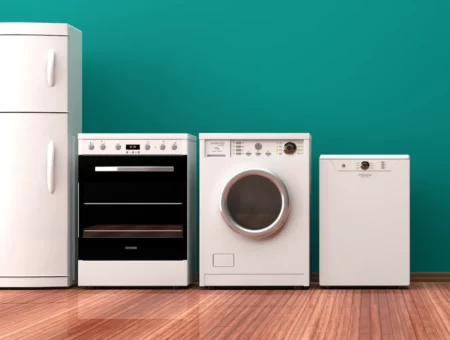 A row of white appliances for rental property including a fridge, oven, washing machine and dishwasher