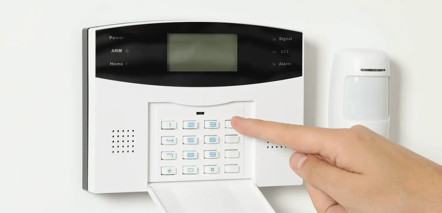 A person setting a house alarm by using the keypad