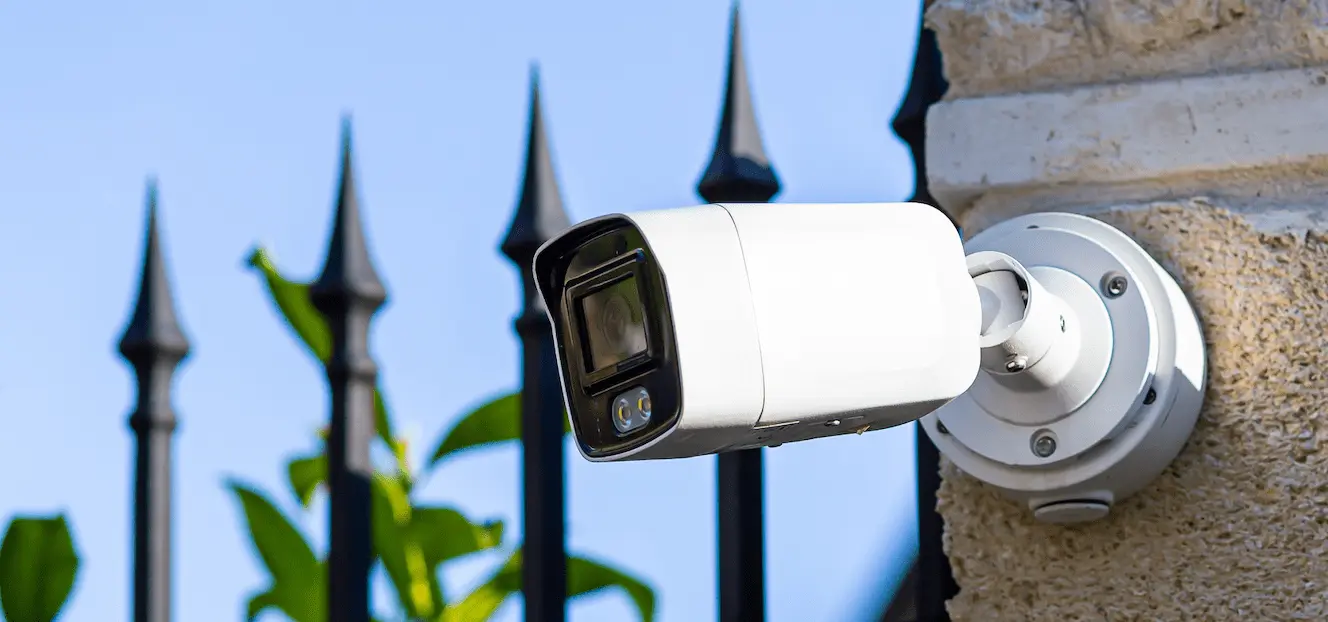 A white security camera attached to the outside of the property