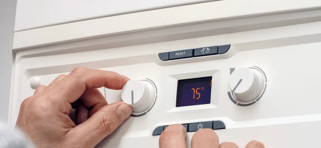 A person adjusting the settings on a boiler
