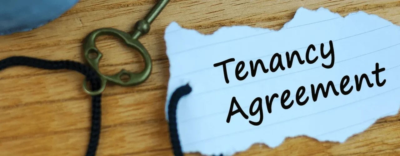 A key with a piece of paper attached. The paper says tenancy agreement