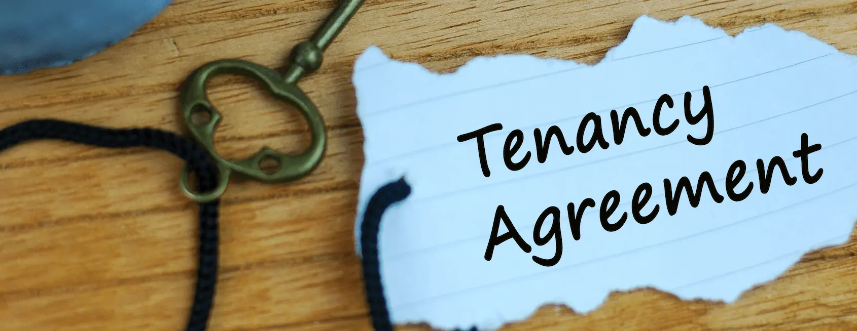 A key with a piece of paper attached. The paper says tenancy agreement