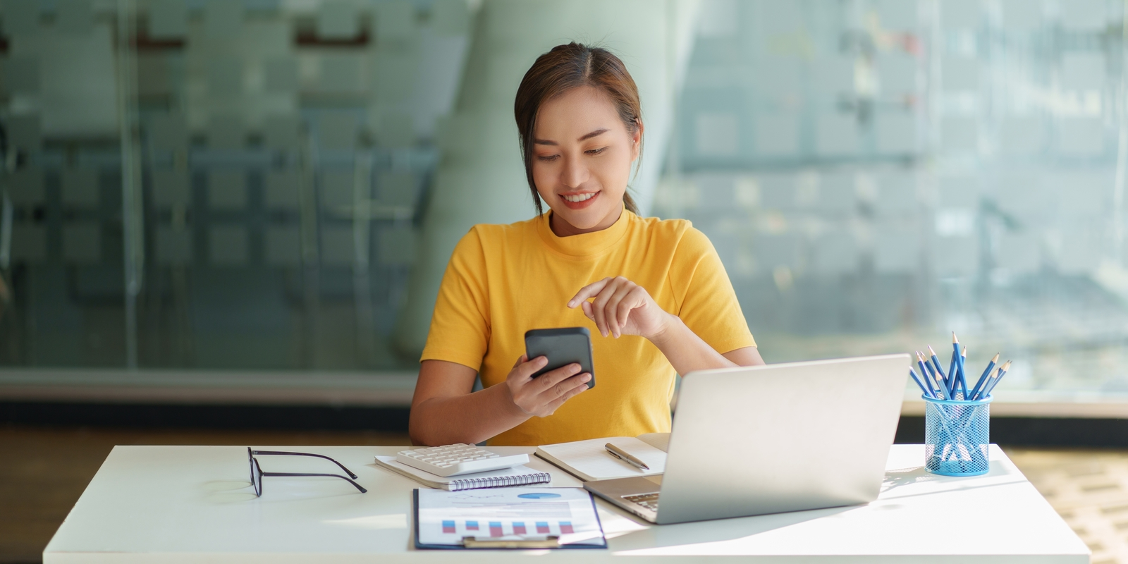 A tenant sat at her laptop about to use open banking on her phone.