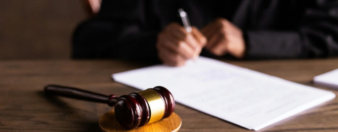 An image of a gavel and someone signing a legal document