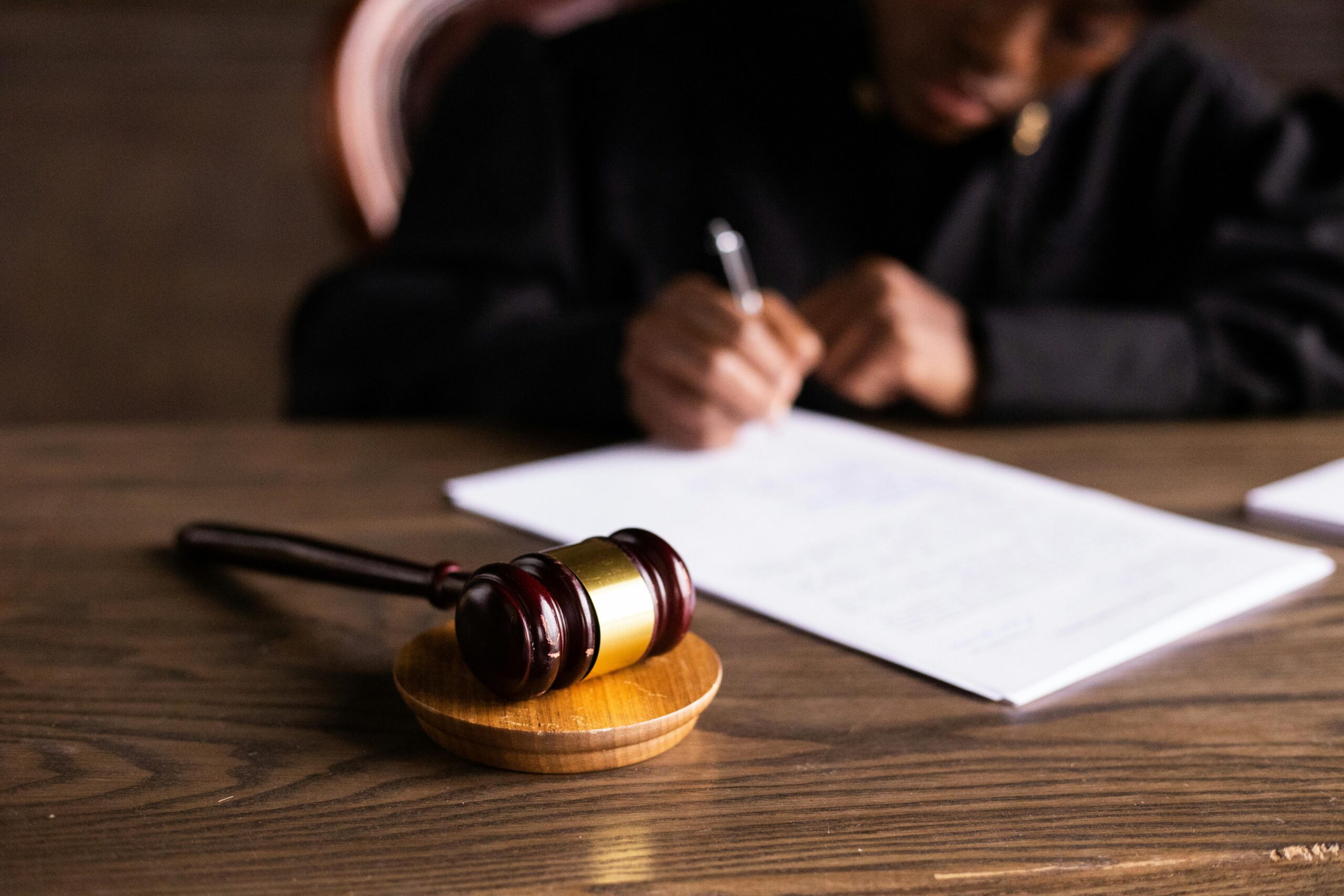 An image of a gavel and someone signing a legal document