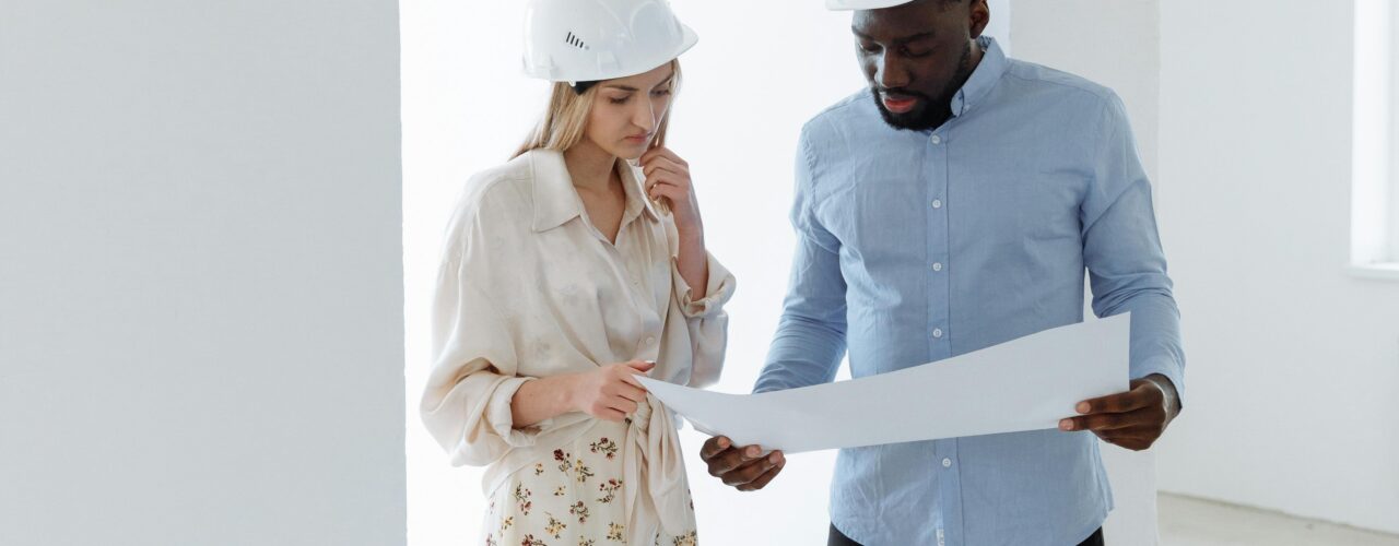 Two people with hard hats on looking at documentation