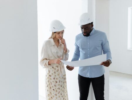 Two people with hard hats on looking at documentation