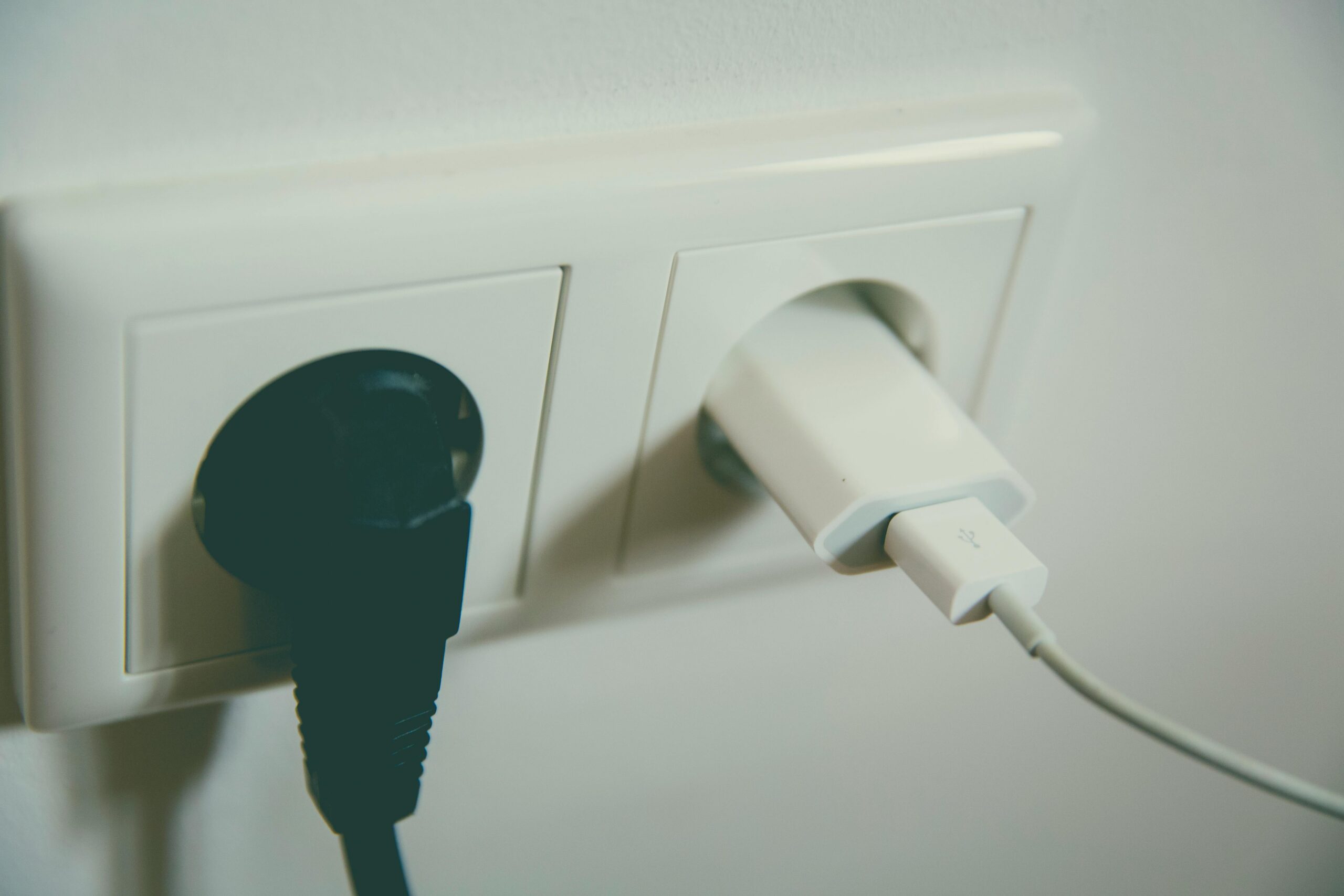 Two chargers in plug sockets to represent electrical safety in a holiday let