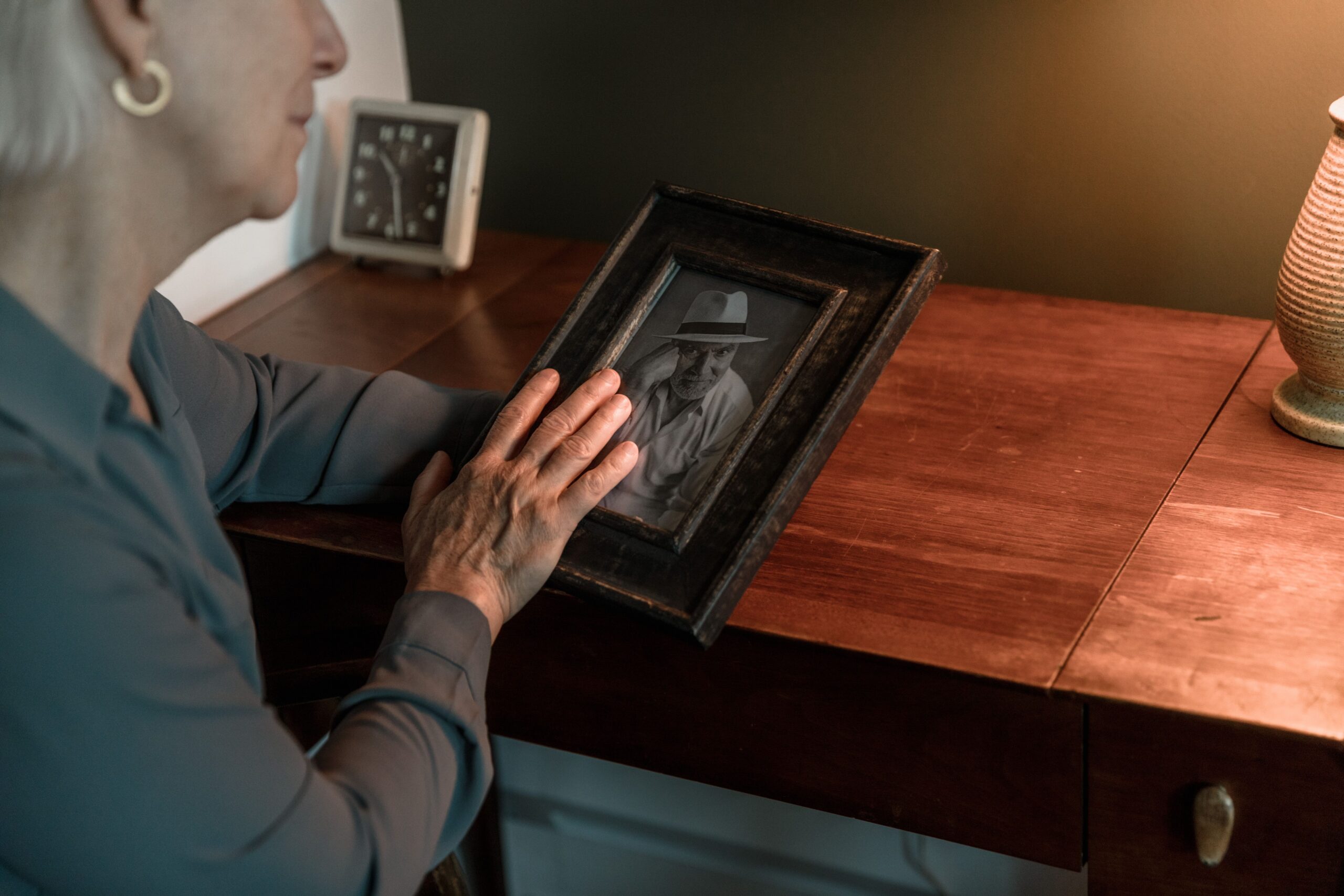 An elderly woman looking at a picture of her deceased husband.