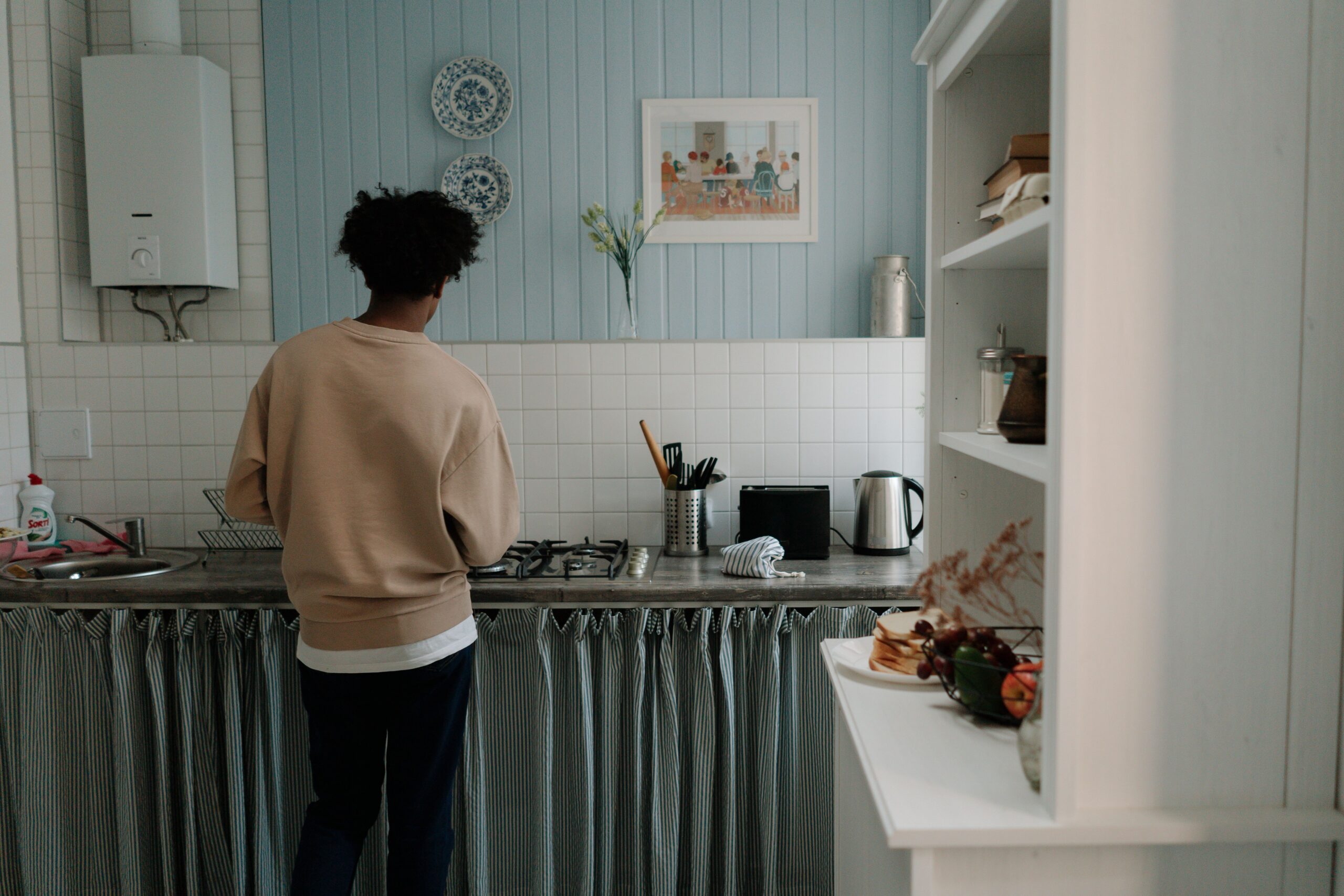 A man standing in his kitchen with a boiler.