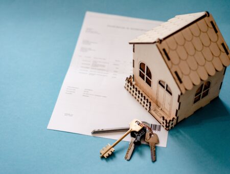 An image of a model house with house keys on top of a tax document